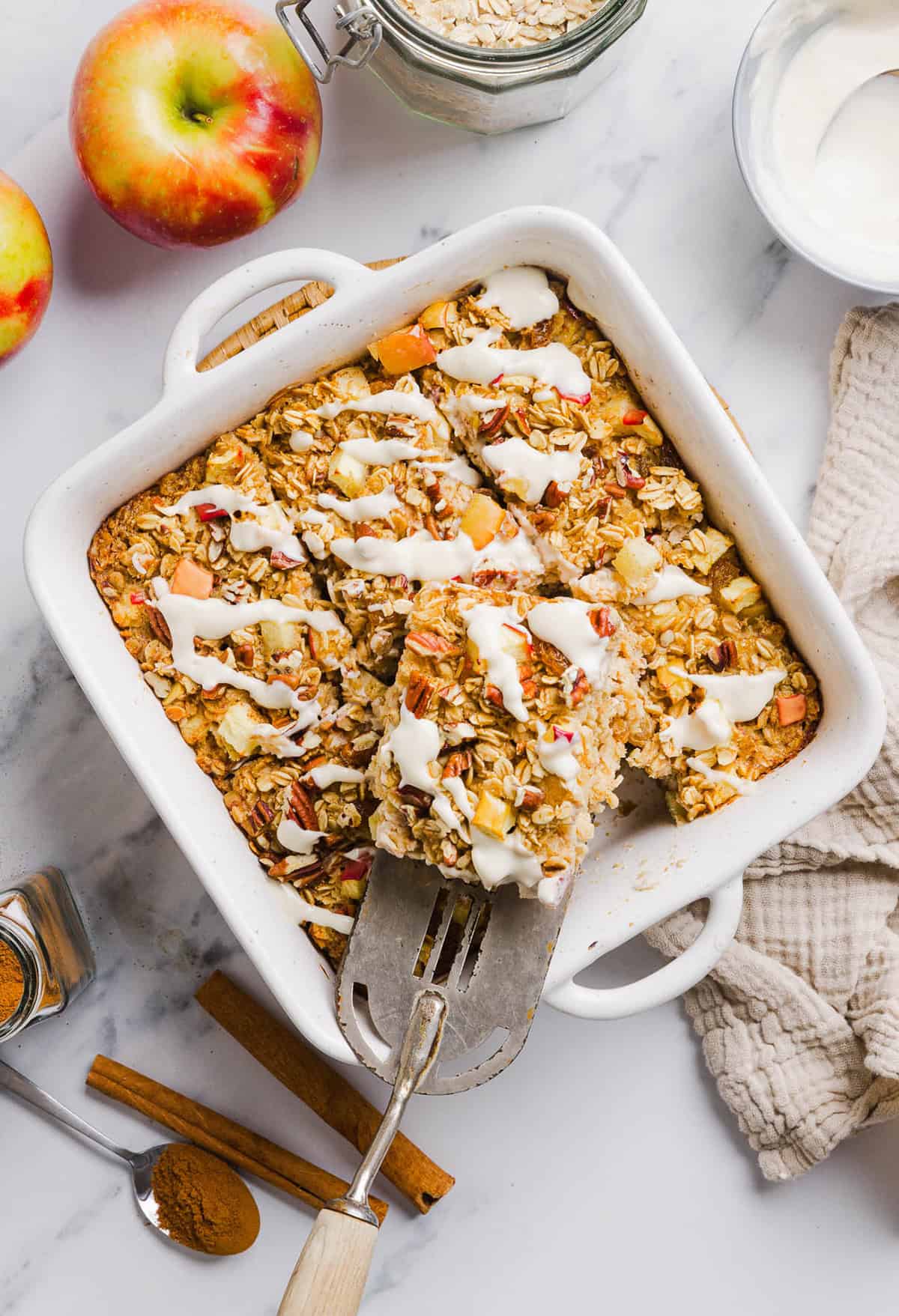 This Apple Cinnamon Baked Oatmeal is a cozy breakfast made with wholesome oats, shredded apples, and warm spices while naturally sweetened with maple syrup and plump raisins! We also topped this with crunchy pecans and a delicious maple cream cheese glaze!
